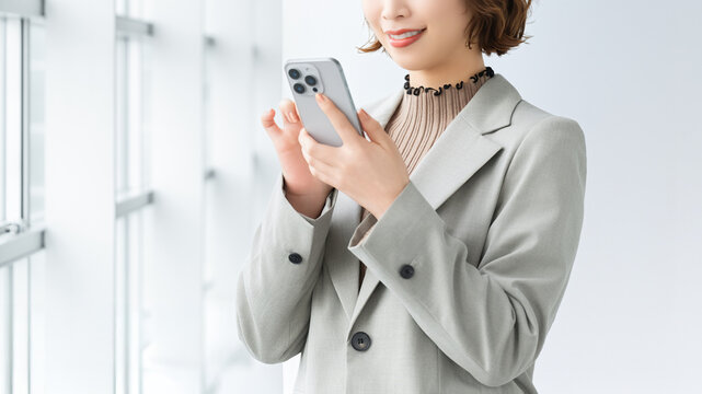 スマートフォンを使う笑顔の女性・ビジネスウーマン