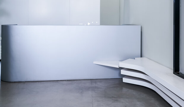 Minimalist grey curved reception desk with white layered bench and green pothos plants in modern office lobby