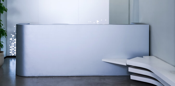 Minimalist grey curved reception desk with white layered bench and green pothos plants in modern office lobby