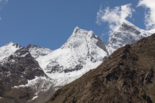 View of the snow-capped peaks of the Zanskar range with rugged rocky slopes and glaciers under a clear blue sky in Zanskar, Ladakh, India.