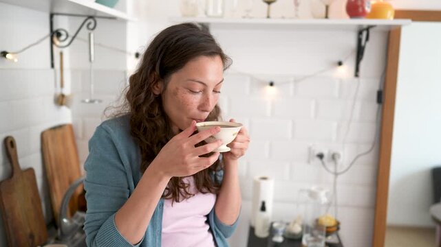 Serene woman savoring first sip of freshly brewed aromatic black coffee during relaxing morning at home. Slow living, mindful coffee ritual, personal pleasure, positive mindset for beginning new day.