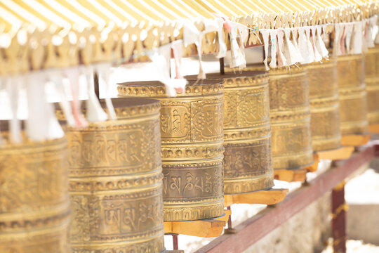 View of traditional brass prayer wheels with intricate Tibetan inscriptions at a monastery in Leh, Ladakh, India.