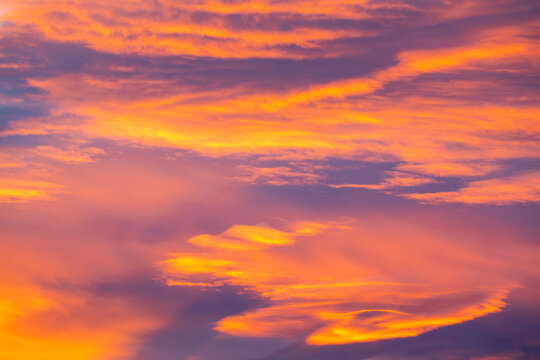 View of a vibrant sunset sky with dramatic orange, yellow, and purple clouds in Stranda, More og Romsdal, Norway.