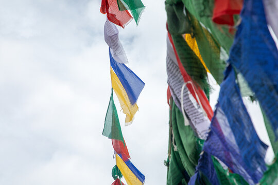 View of colorful Tibetan prayer flags fluttering in the wind against a cloudy sky in Leh, Ladakh, India.