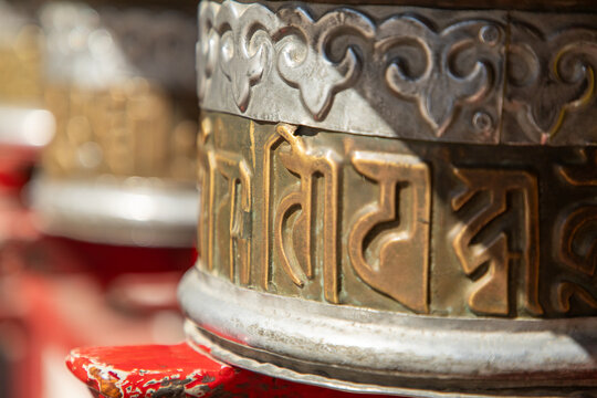 View of a traditional Tibetan Buddhist prayer wheel with intricate metal engravings and Sanskrit mantras in Leh, Ladakh, India.