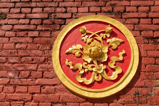 View of a golden floral relief sculpture on a red brick wall at Namobuddha Monastery in Simalchaur Syampati, Bagmati Province, Nepal.