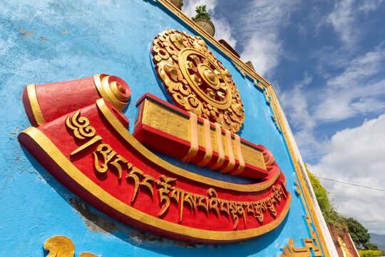 View of the ornate gold and red Buddhist emblem on a blue wall at Namobuddha Monastery in Simalchaur Syampati, Bagmati Province, Nepal.