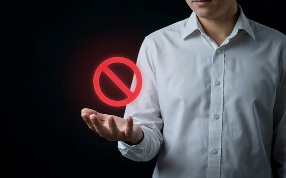 Businessman holding glowing red prohibition sign above palm against dark background for corporate policy restriction concept