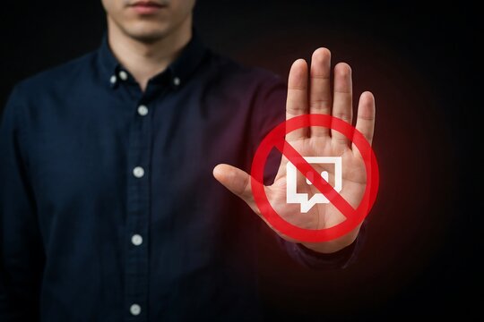 Man showing stop gesture with red prohibited sign over digital chat icon on dark background studio shot