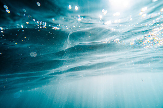 View of the turquoise waters and sunlight filtering through the surface at Lulworth Cove, United Kingdom.