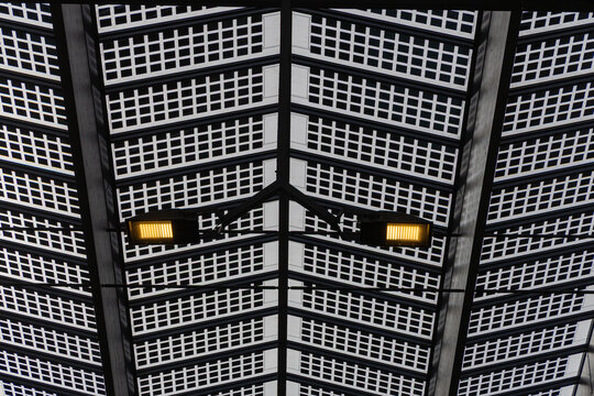 View of the modern glass and steel roof structure of Rotterdam Centraal station, featuring a geometric grid pattern and illuminated spotlights, Rotterdam, South Holland, Netherlands.