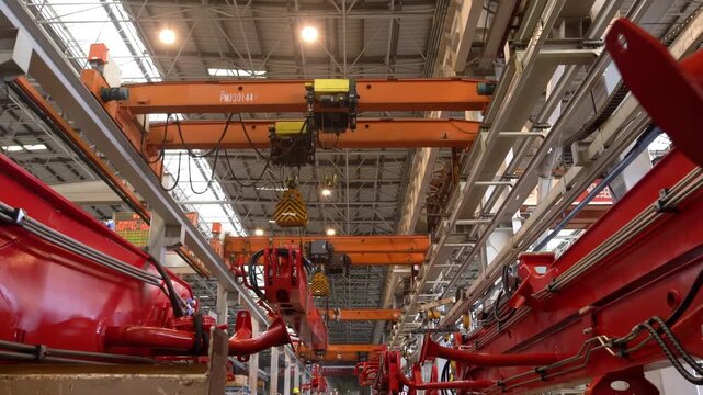 Dedicated factory workers checking status, operating large advanced robotic machines, well-equipped industrial manufacturing facility precision engineering, increase productivity, skilled craftsman