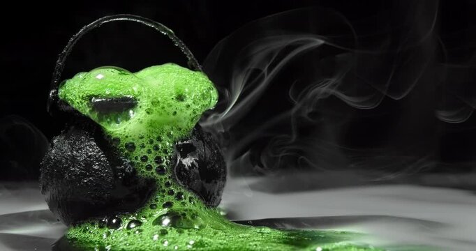 Eerie green ooze bubbling from black cauldron. Scary witch's brew or magical enchanted potion for spooky Halloween witchcraft. Occult or black magic spell of glowing green goo overflowing and fizzy.