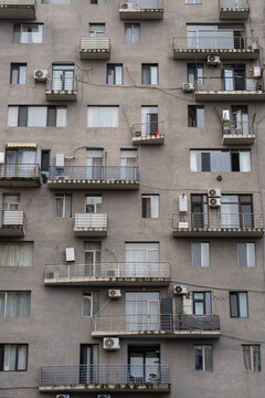 Concrete residential apartment building with haphazard drilling holes in walls on facade in Batumi, disfiguring of apartment house with chaotic balconies by routing air conditioner pipes on exterior.