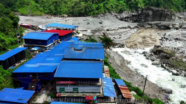 Kathmandu, Bagmati Province, Nepal - 31 August 2026: Aerial view of Mailung Khola Jal Vidhyut Company Limited facility with blue roofs along a rushing river in mountains.