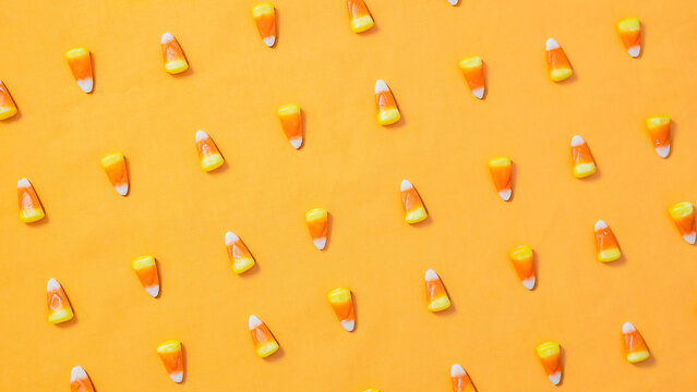 Candy corn on an orange background set in an alternating pattern