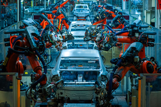 Industrial robotic arms assembling car bodies on automated automobile production line