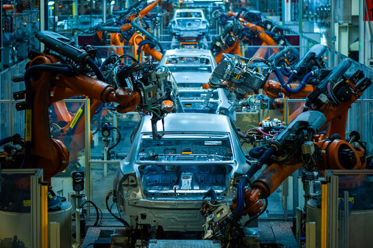 Industrial robotic arms assembling car bodies on automated automobile production line
