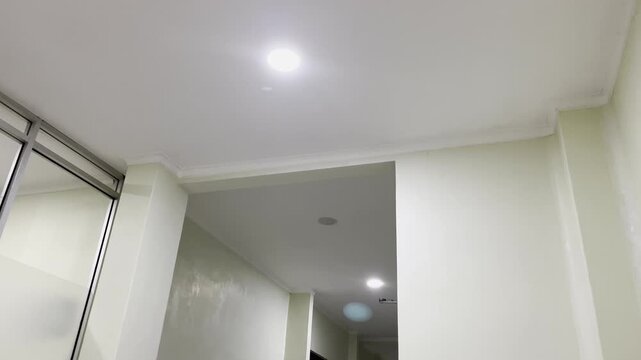 Minimalist white ceiling corner with glowing downlight lamp