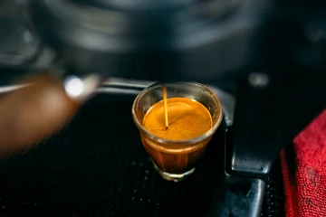 Macro shot of perfect espresso extraction with rich crema pouring into a glass. © artrachen