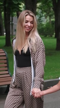 Vertical video. Casual family stroll. Walk park. Positive smiling mother playful son relaxing together enjoying talking in lush green summer outdoor.