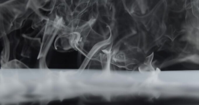 Real wispy smoke exploding outwards from center stage. Ominous smoke creating stormy blast with a mysterious haunting aura of the paranormal or a spooky Halloween background or eerie visual effect.