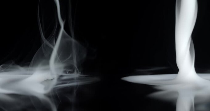 Real wispy smoke swirling on both sides with empty center stage. Vortex of wispy smoke spinning creating a mystical ghostly aura of the paranormal or a spooky Halloween background visual effect.