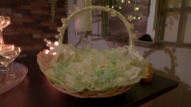 Basket filled with pale green wrapped wedding favors sits on a decorated reception table