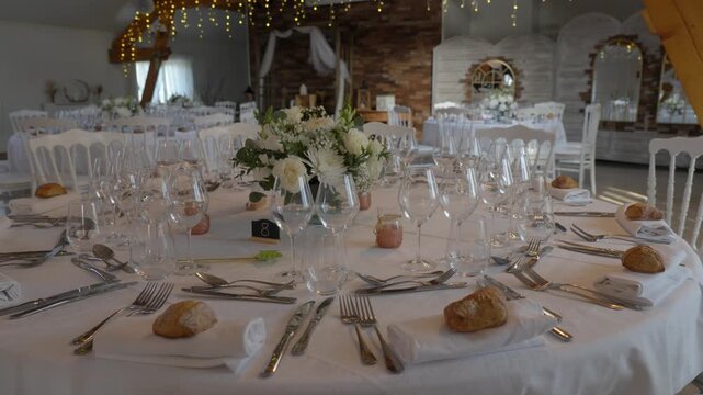 Round wedding reception table is fully set beneath warm string lights in a rustic venue, rise ascend