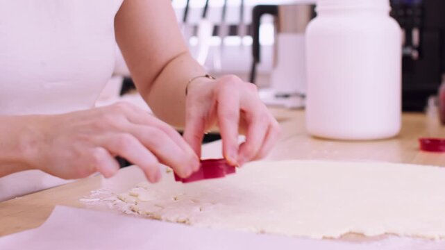 Pastry making. Dough tool. Woman baker hand making homemade cookies tasty treat with star shape cutters at light kitchen countertop.