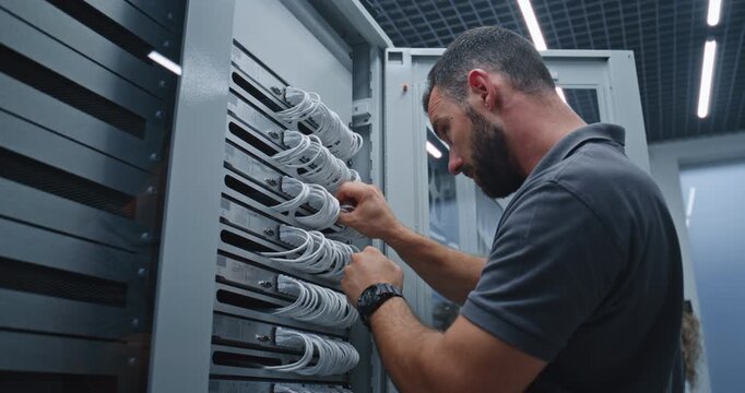 Server Room Technician Connects Ethernet Cables to Server Ports, Carefully Checking Hardware Connections and Network Wiring to Maintain Reliable Connectivity and Efficient Infrastructure Performance.