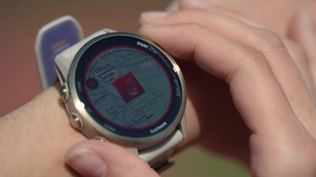 Close up of a Garmin GPS smartwatch displaying a navigation map while a person operates the touchscreen. Wearable technology for running, cycling, hiking and outdoor navigation.