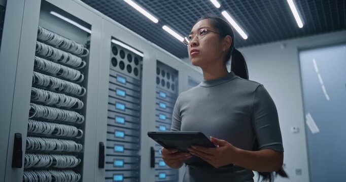 IT Specialist Inspects Organized Patch Cables and Technical Information on Tablet Inside Modern Server Room. Network Infrastructure, Connectivity Monitoring, Maintenance and Data Management Systems.