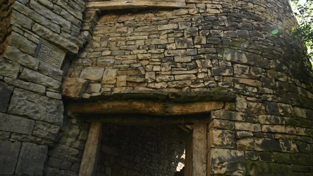Panning across weathered stone wall and rustic entryway