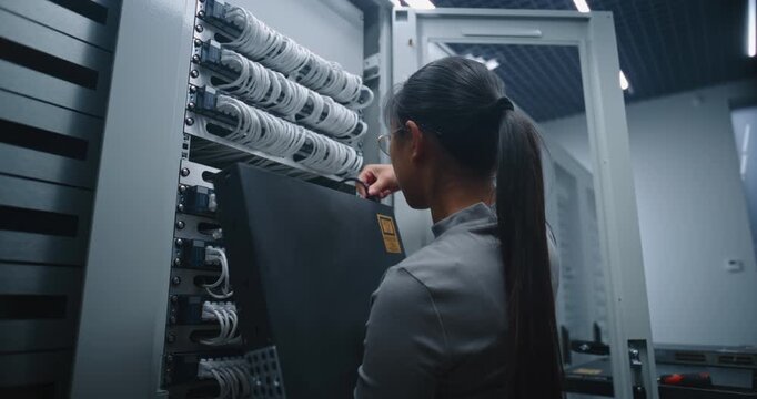 Female IT Engineer Secures New Network Switch Inside Server Rack With Screwdriver and Mounting Screws. Close Technical Workflow, Hardware Installation, Rack Maintenance and Network Infrastructure.