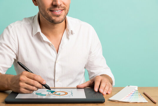 Cropped view of smiling male graphic designer drawing logo with stylus on graphics tablet, branding and creative design concept on mint green background with copy space