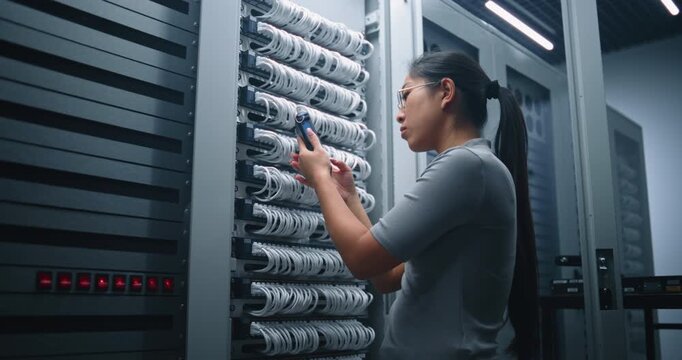 Network Engineer Tests Ethernet Cable With Portable Network Tester inside Server Room. Professional Workflow Demonstrates Cable Certification, Connection Verification and Physical Layer Diagnostics.