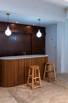 Wooden slat counter and bar stools illuminated by globe pendant lights in modern cafe interior