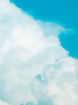 Soft pastel aqua blue sky with fluffy faded cumulus clouds dreamy airy minimalist cloudscape background