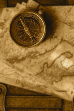Old vintage maps and brass compass on top of a vintage leather luggage case. Vintage travel background backdrop concept.
