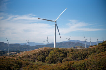 Wind turbines on autumn hills under blue sky © Junho