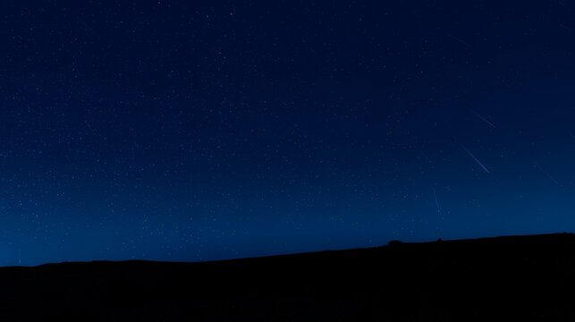 Faint Meteor Trails Drifting Across Midnight Blue Sky Over Ridge