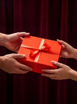 Man giving a red gift box to a woman