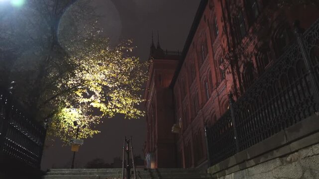 Stockholm, Sweden A night view in autumn of trees and shadows on the facade of the old Sodra Latin high school in the Sodermalm district.  