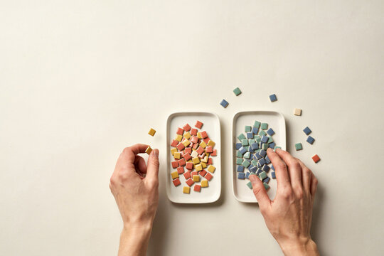 Hands sorting ceramic chips into two trays, seen above