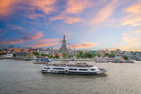 Tourist boat on the Chao Phraya River, with Wat Arun Ratchawararam Ratchawaramahawihan in the background, Bangkok, Thailand captured at sunset against a beautiful sky.