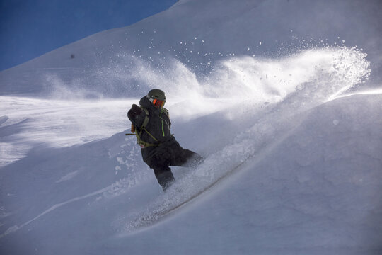 Snowboarder carving a turn in deep powder snow