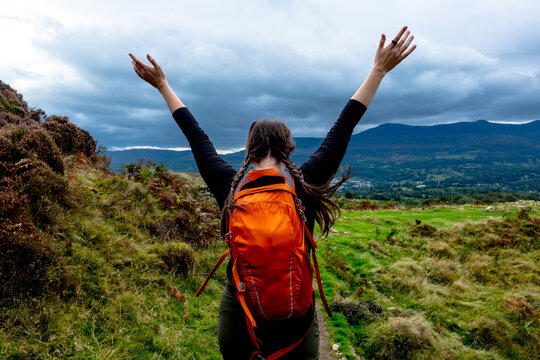 Woman with a backpack raises her arms to the sky