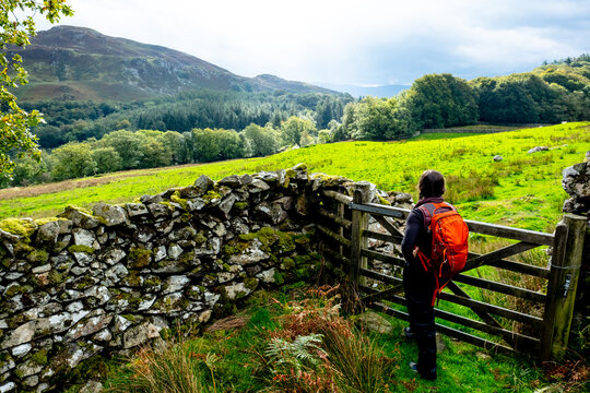 Woman hiker pauses at a rustic gate in the countryside