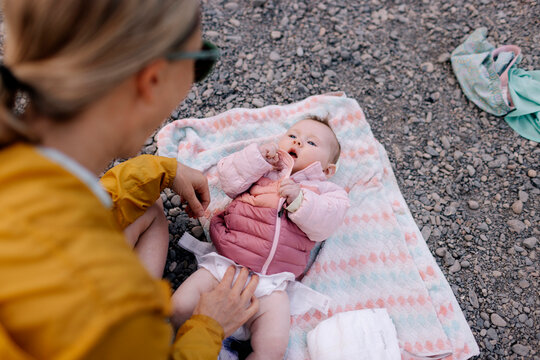Woman changing baby's diaper on a rocky ground